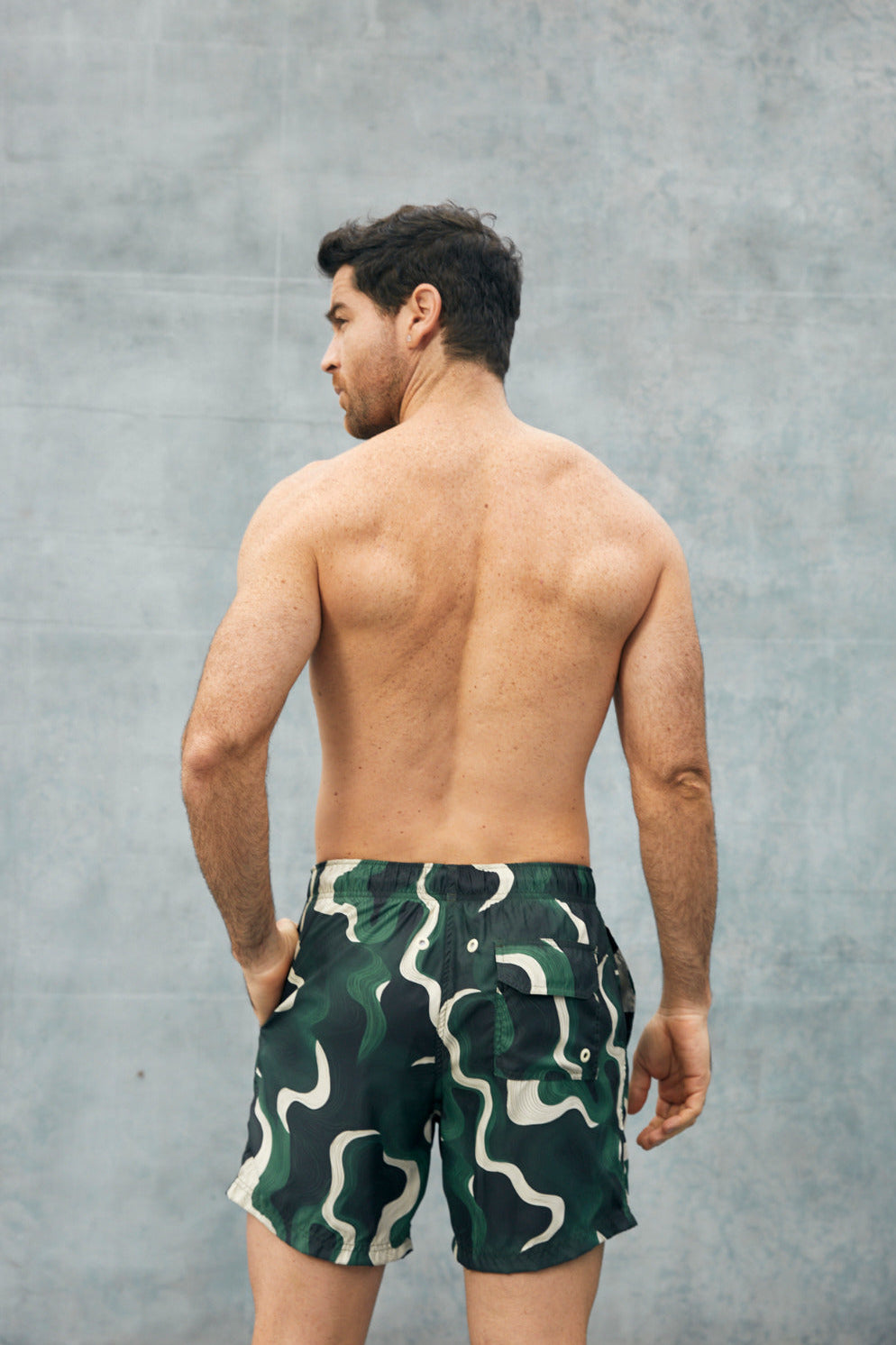 Pantaloneta de baño verde con bolsillo trasero abotonado y diseño ondulado