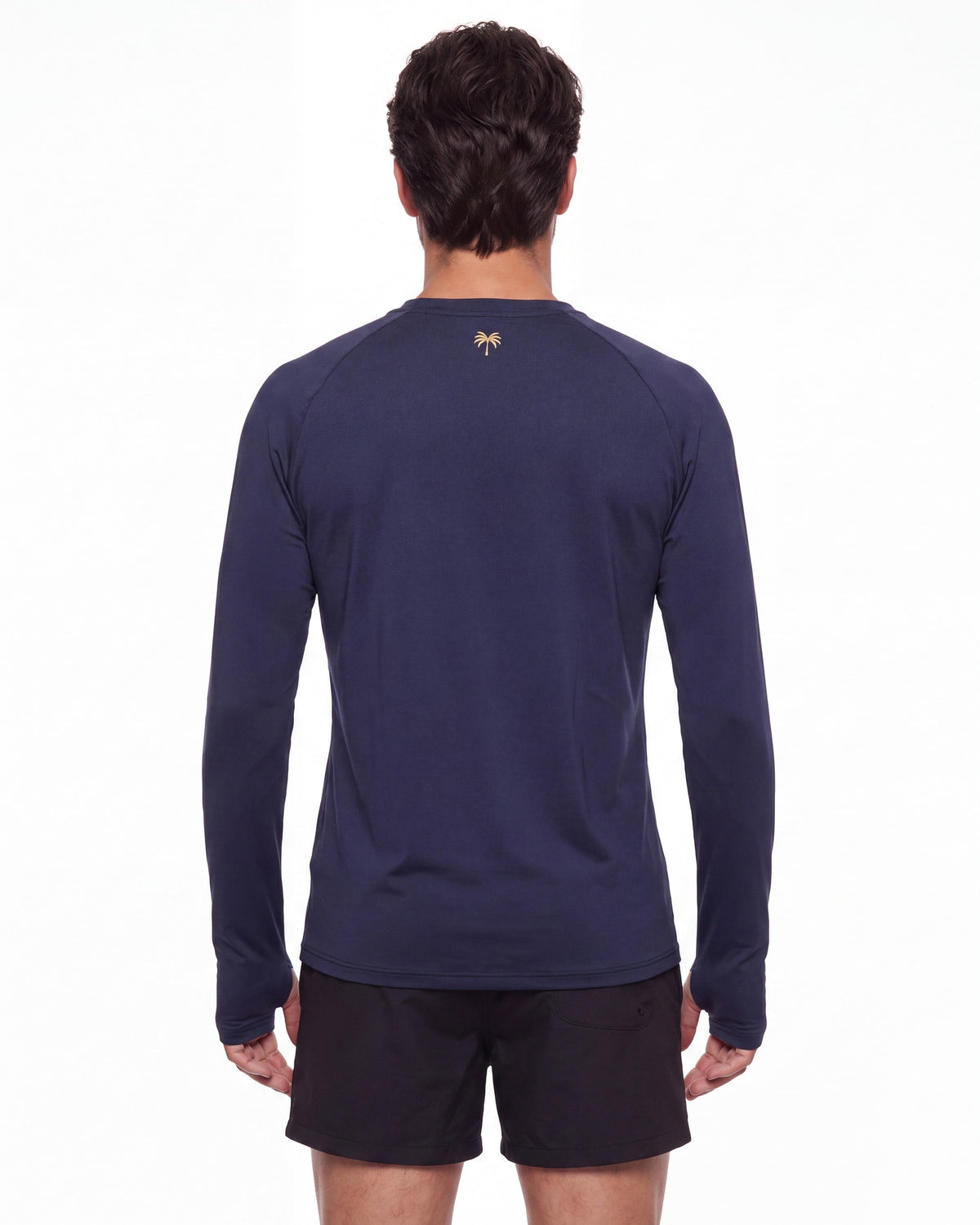 Hombre de espaldas con rashguard FIJI azul marino; la palmera dorada queda centrada