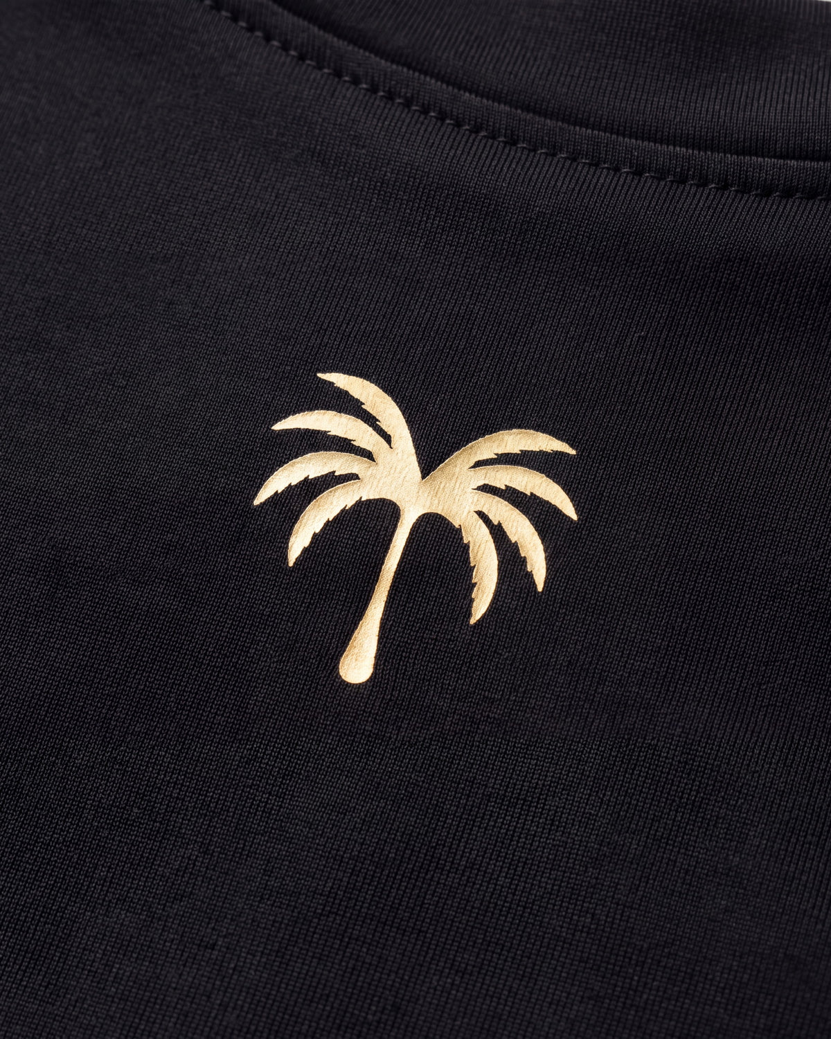 Palmera dorada estampada sobre el tejido técnico negro del rashguard FIJI