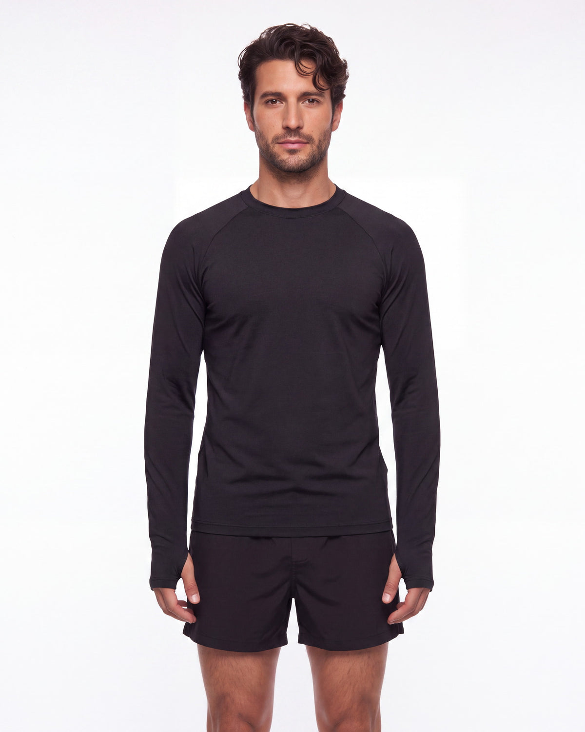 Hombre con rashguard FIJI negro y pantaloneta de baño, de pie de frente