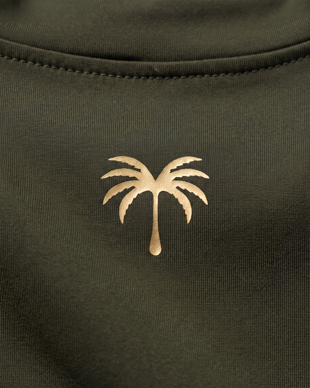 Palmera dorada estampada sobre el tejido técnico verde oliva del rashguard FIJI