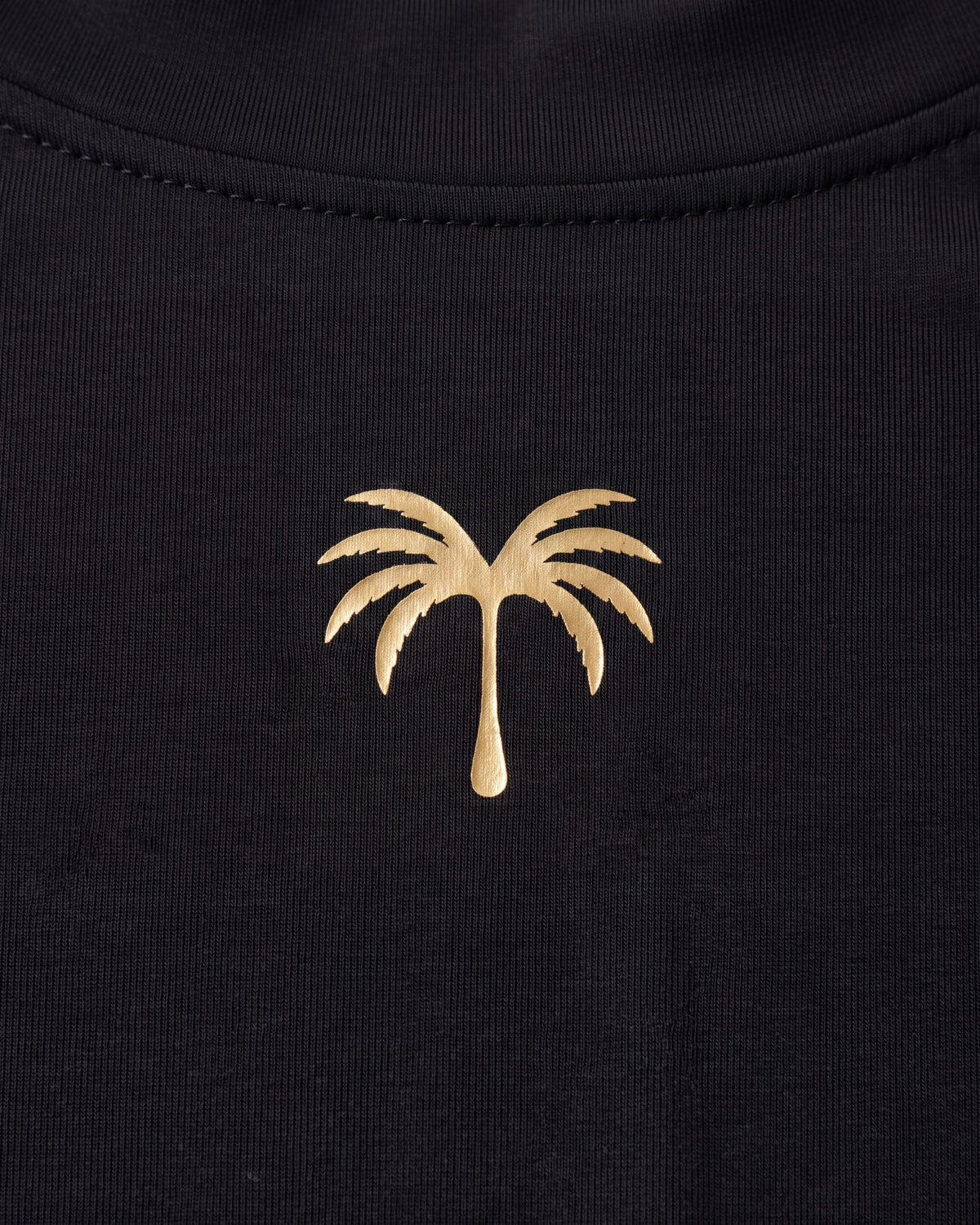 Palmera dorada estampada sobre el tejido negro del rashguard de niño