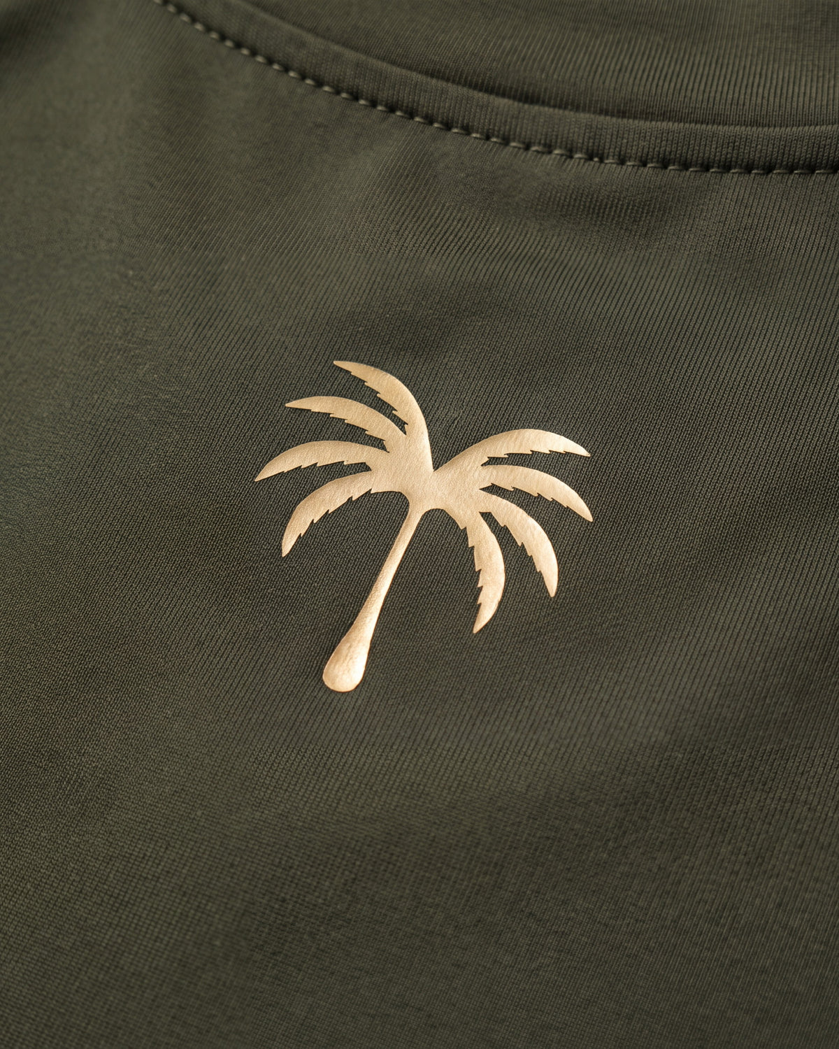 Palmera dorada estampada sobre el tejido verde oliva del rashguard de niño
