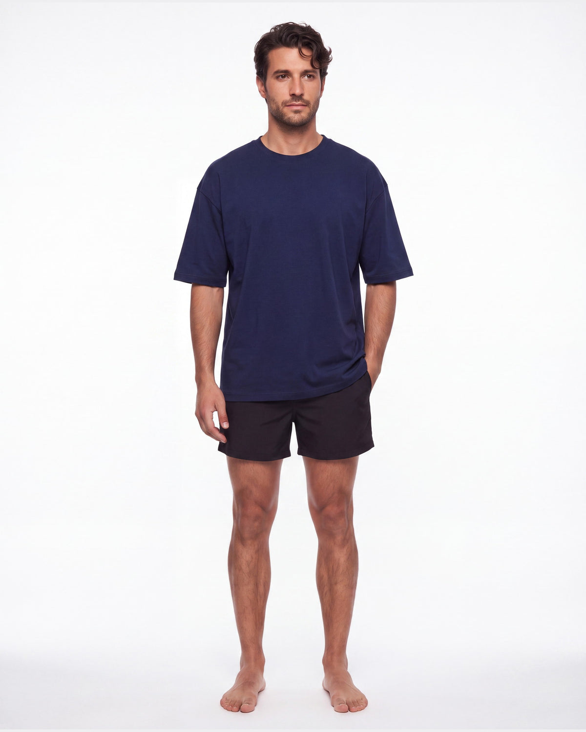 Hombre con camiseta KAI azul marino y pantaloneta de baño, de pie de frente