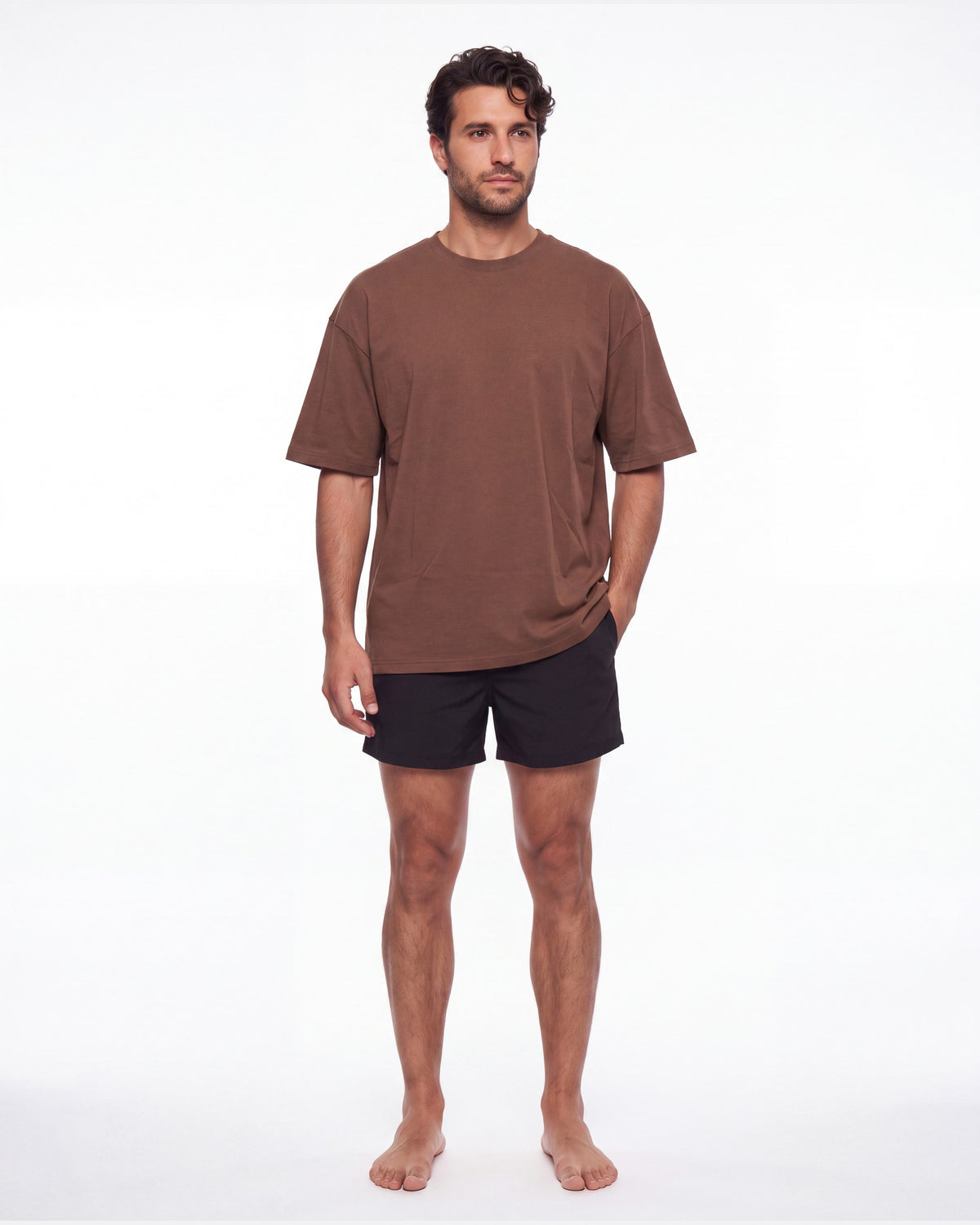 Hombre con camiseta KAI café y pantaloneta de baño, de pie de frente