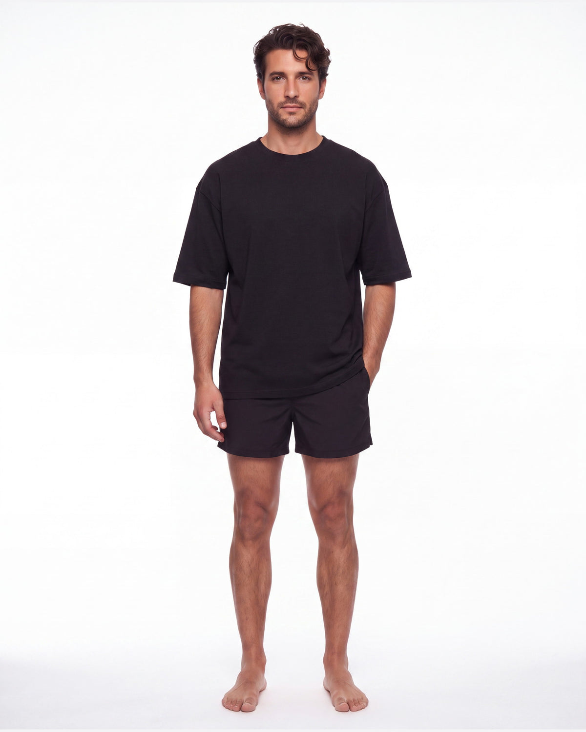 Hombre con camiseta KAI negro y pantaloneta de baño, de pie de frente