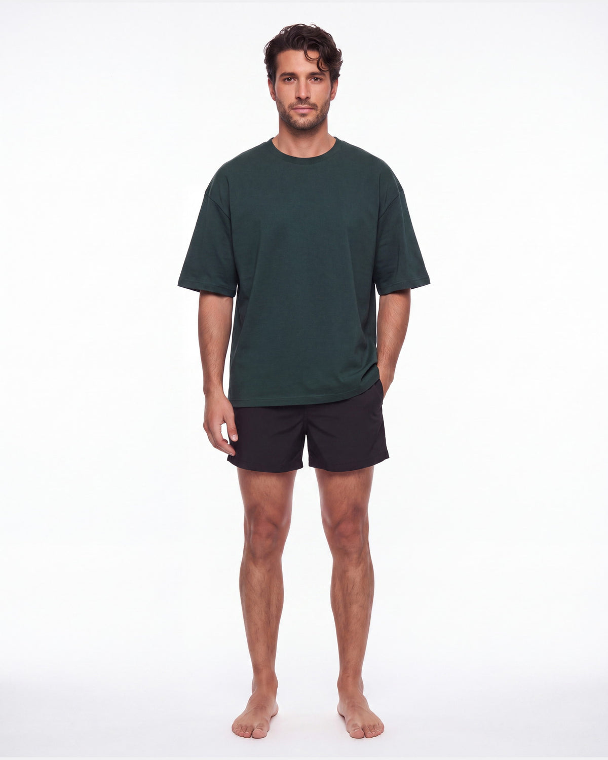 Hombre con camiseta KAI verde botella y pantaloneta de baño, de pie de frente