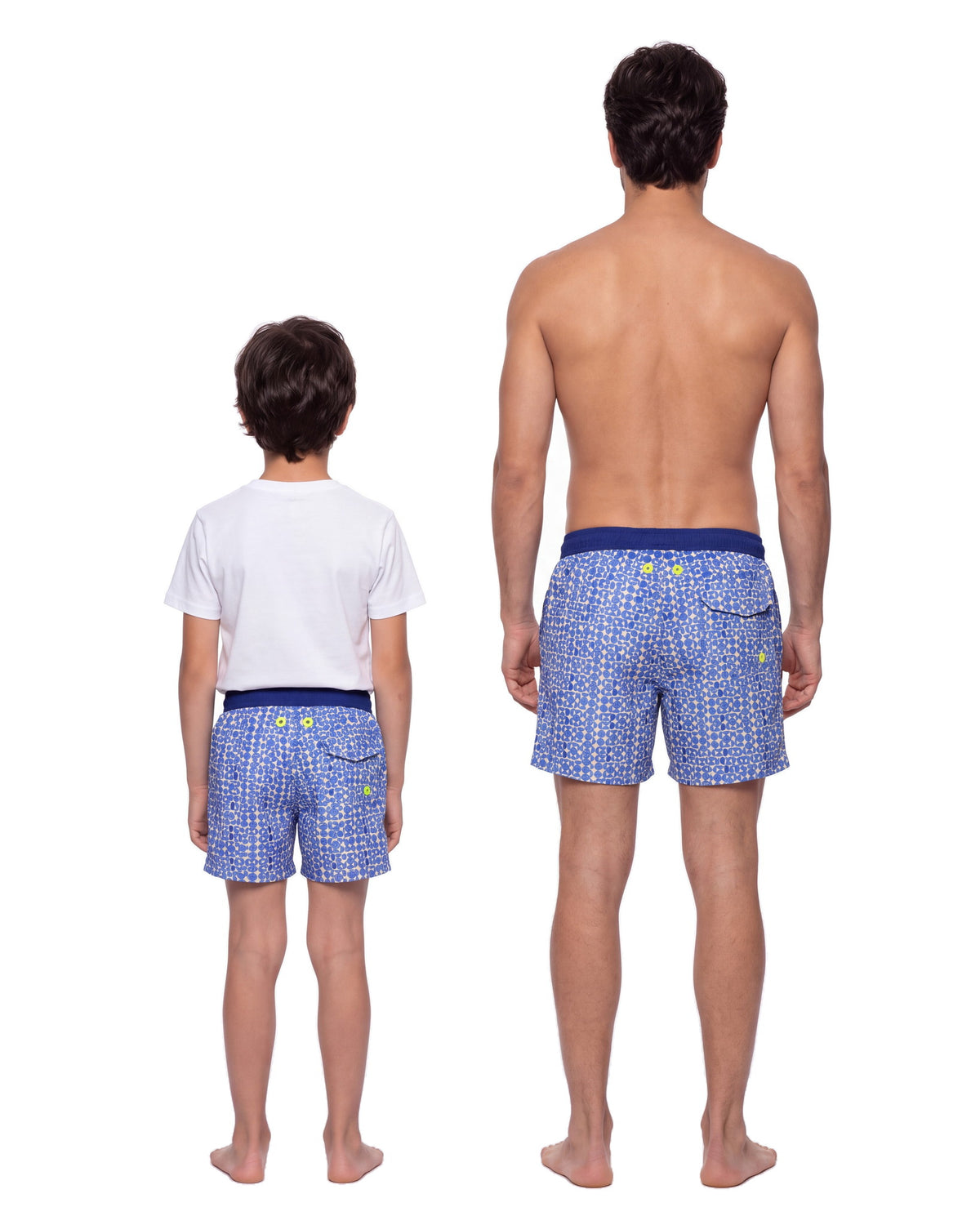 Niño y hombre con la misma pantaloneta LOS ROQUES, de espaldas sobre fondo blanco