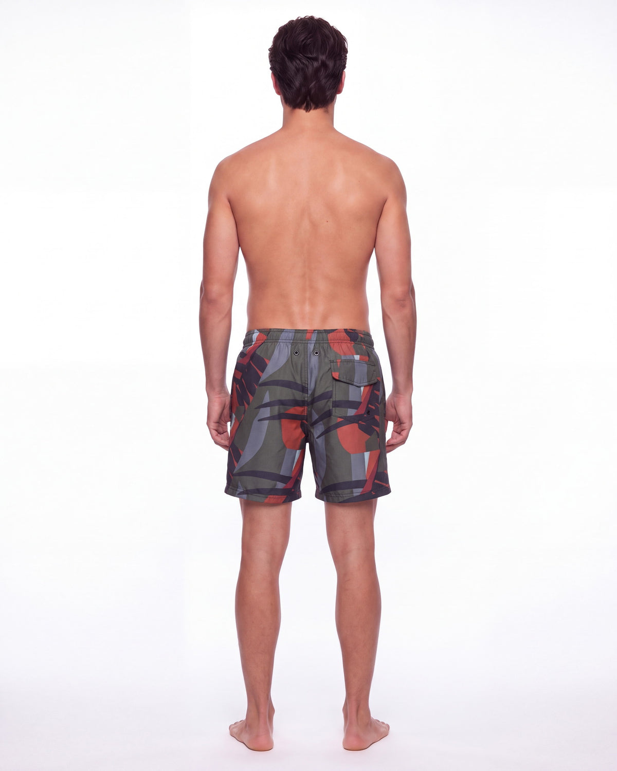 Hombre con pantaloneta de baño OIA gris carbón con bloques angulares, de espaldas